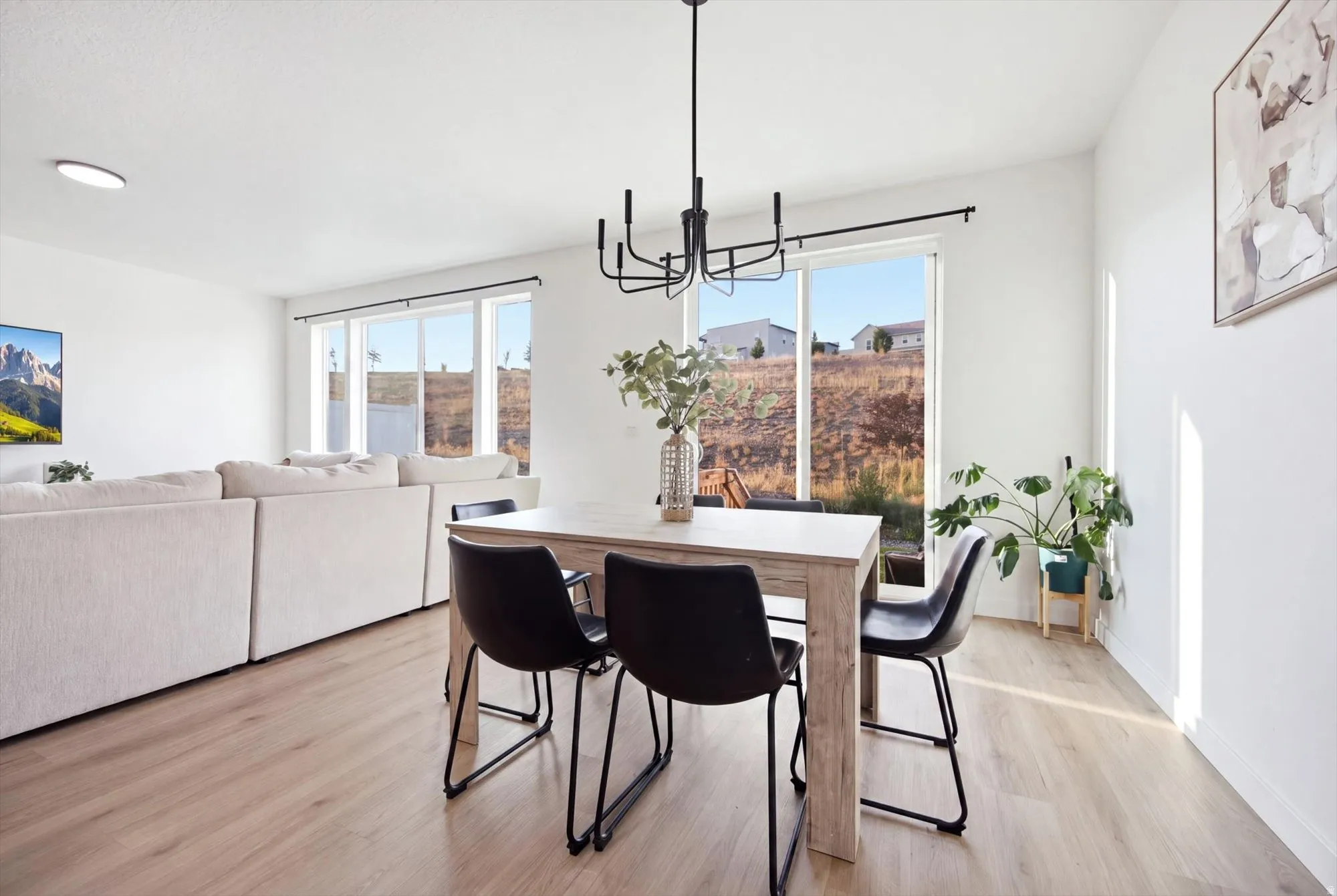 Wood-finish flooring throughout, multiple large windows, and a contemporary black chandelier