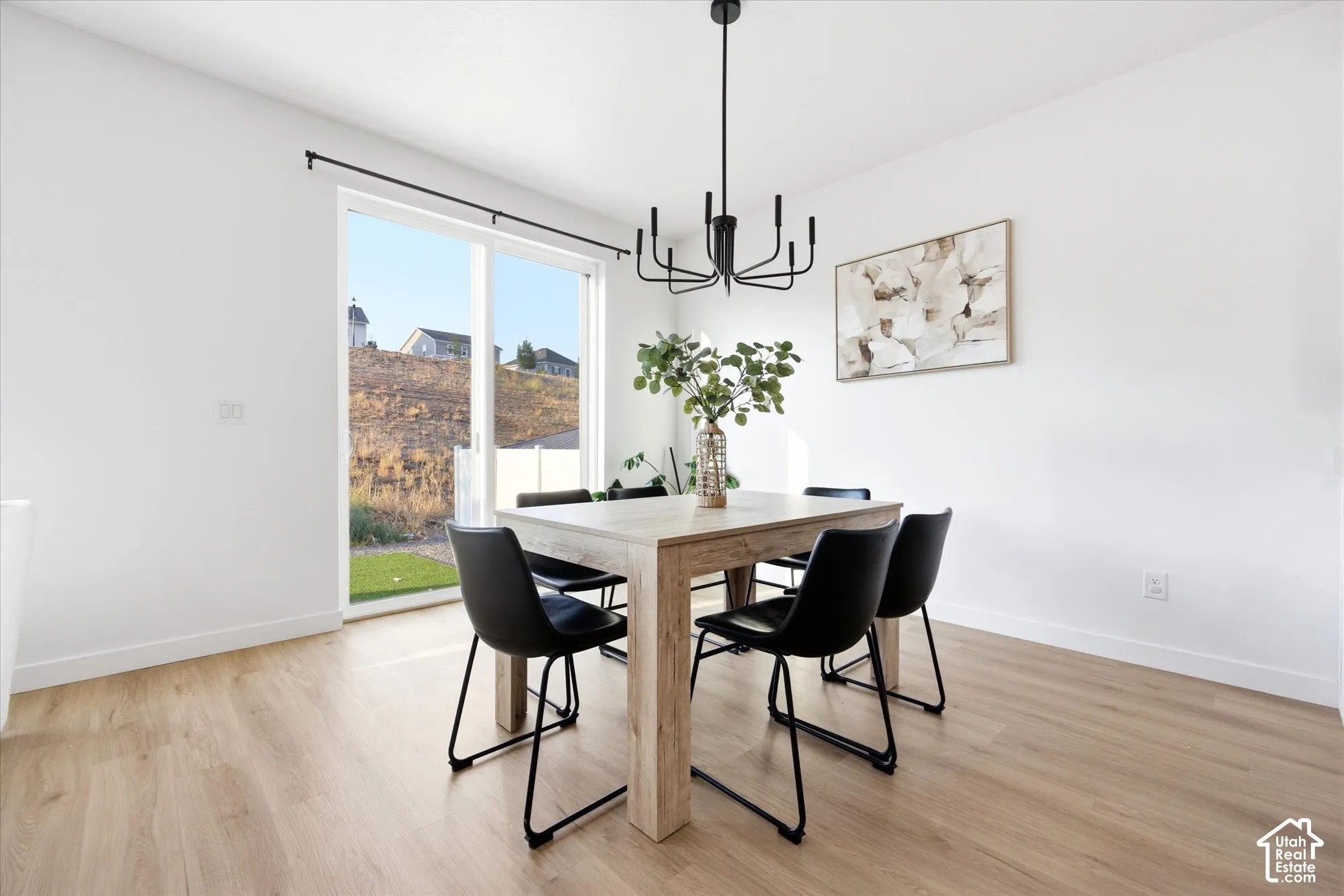 Sliding glass door leading to exterior, wood-finish flooring, and a modern black chandelier