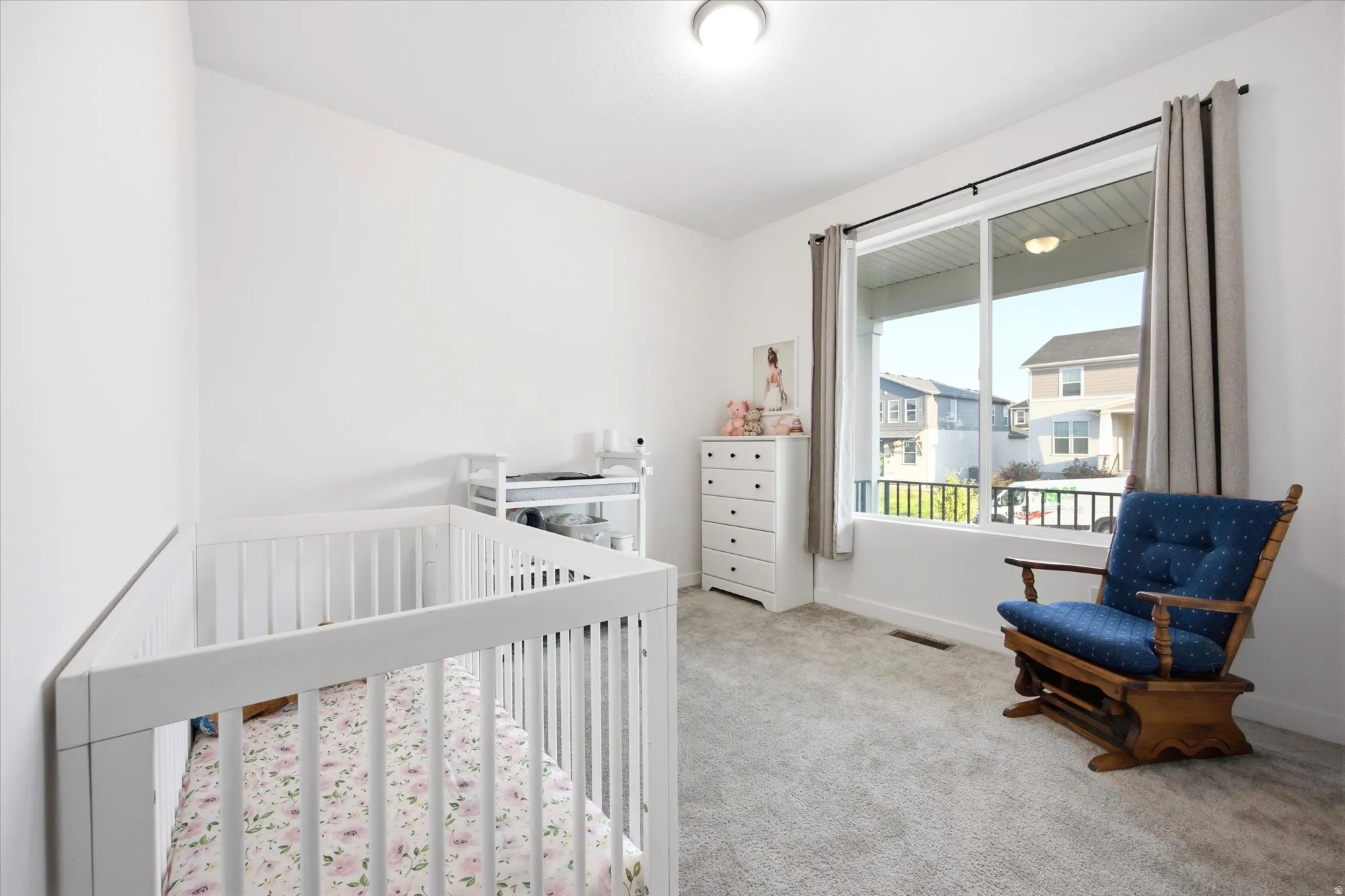 Bright interior space with light-colored carpeting, white wall finishes, and a large window