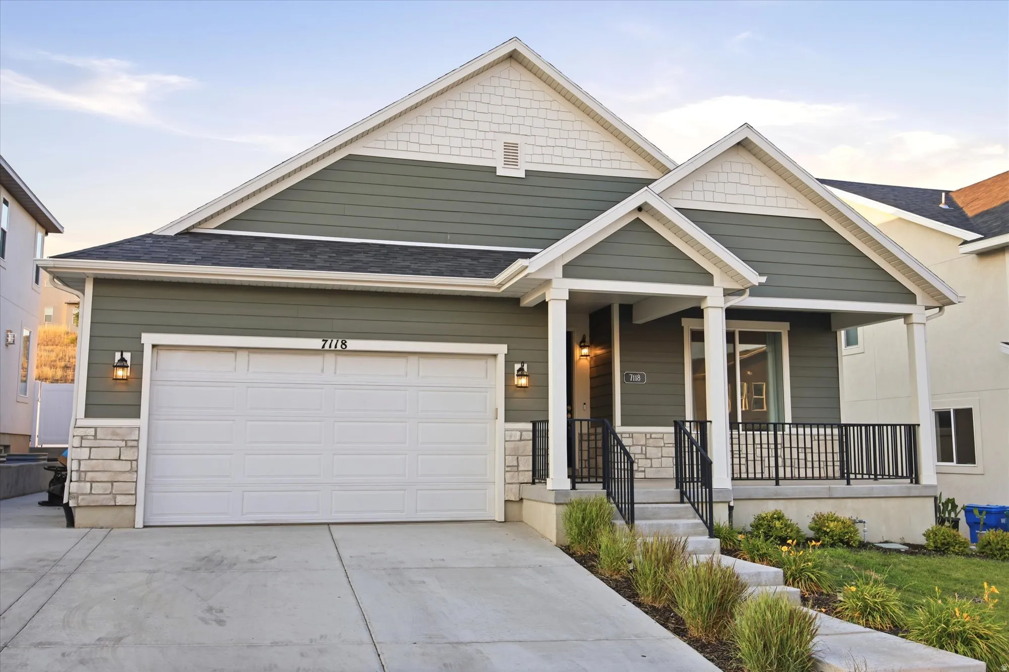Craftsman-style exterior with a covered porch, stone accents, horizontal siding, and an attached two-car garage