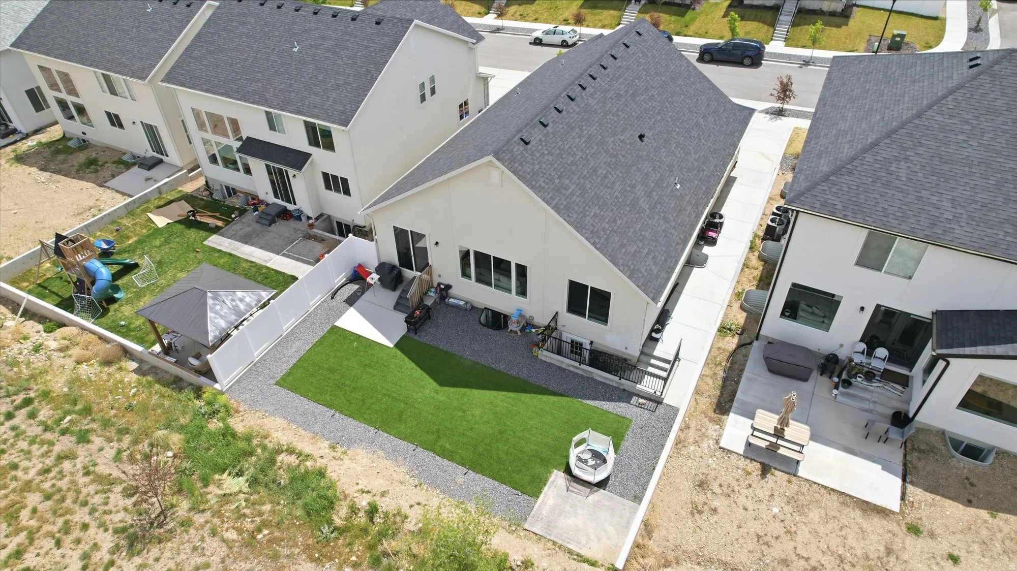 Rear exterior featuring a patio, a section of artificial turf, gravel landscaping, and a white privacy fence