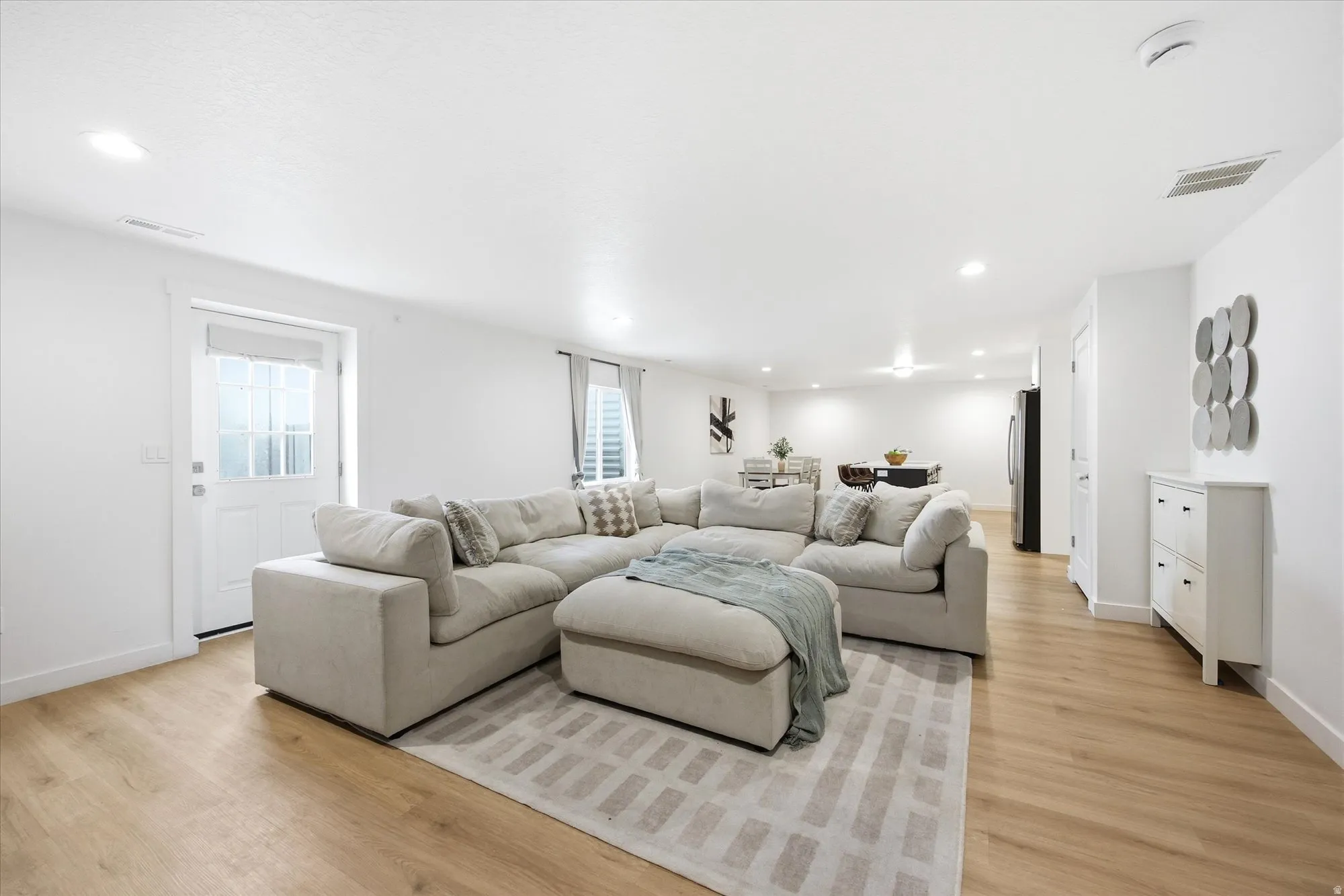 Recessed lighting illuminates the open-concept living space with wood-finish flooring