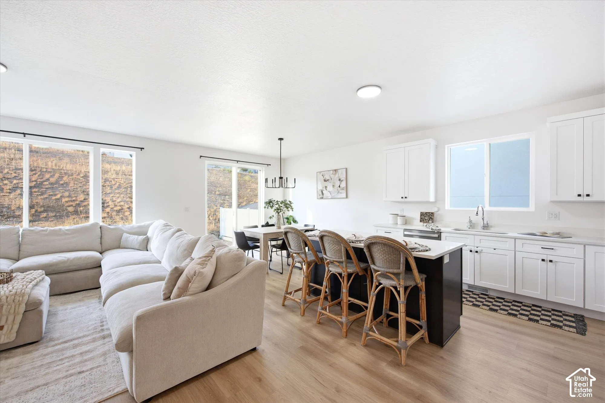 Open-concept living area with wood-finish flooring, white cabinetry, and a kitchen island with a light-colored countertop