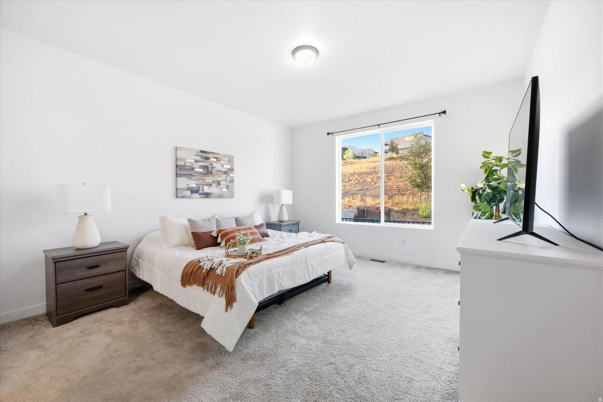 Carpeted bedroom featuring white walls, a large window with a dark rod, and a ceiling-mounted light fixture