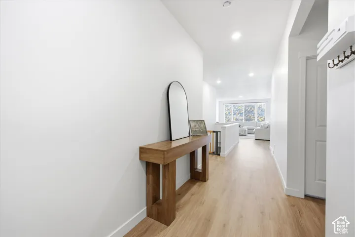 Recessed lighting illuminates the wood-finish flooring and white walls