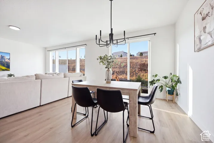 Wood-finish flooring throughout, multiple large windows, and a contemporary black chandelier