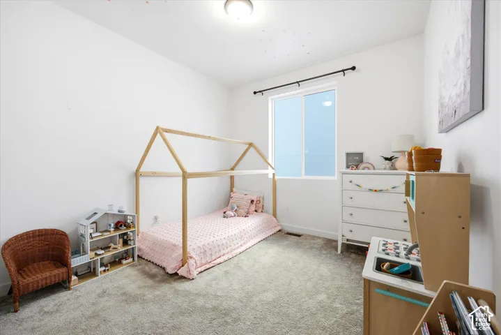 White walls, neutral carpeting, and a window with a black rod