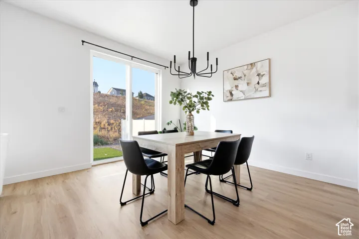 Sliding glass door leading to exterior, wood-finish flooring, and a modern black chandelier