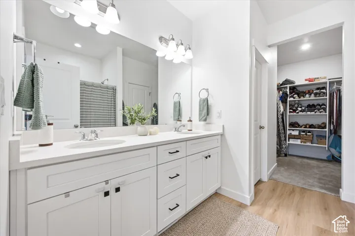 Dual vanity with white cabinetry, polished chrome fixtures, and a large mirror