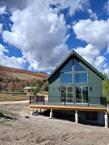 Gable roofline with large picture windows, elevated trex-finish deck with black railings.