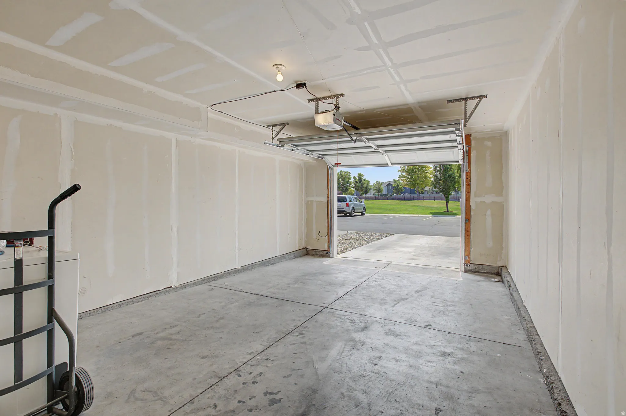 Spacious garage with concrete flooring, drywall-finished walls and ceiling, and an automatic garage door opener
