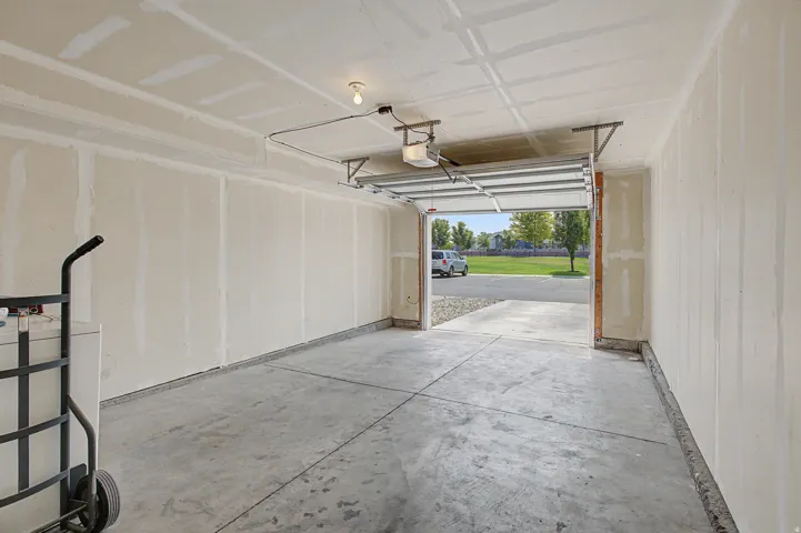 Spacious garage with concrete flooring, drywall-finished walls and ceiling, and an automatic garage door opener
