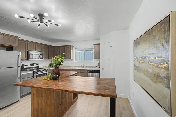 Stainless steel appliances, wood-finish flooring, wood-finish kitchen island, recessed lighting, and a modern sputnik-style ceiling fixture