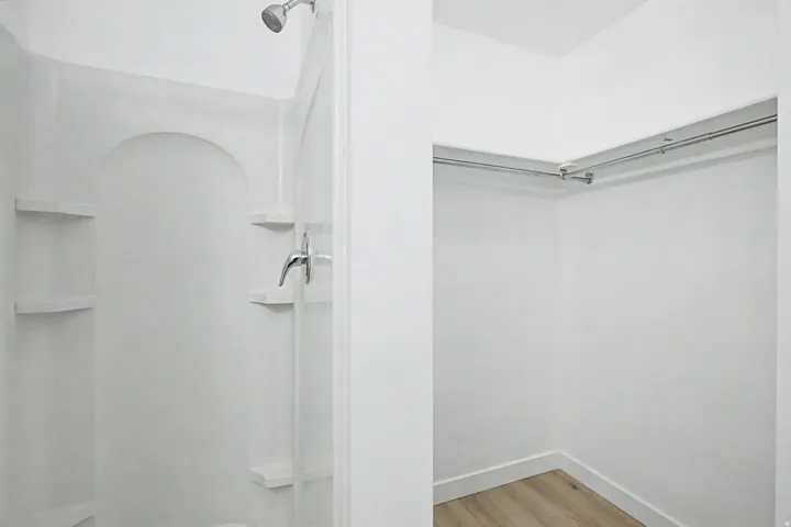 Walk-in shower with integrated shelving and chrome fixtures