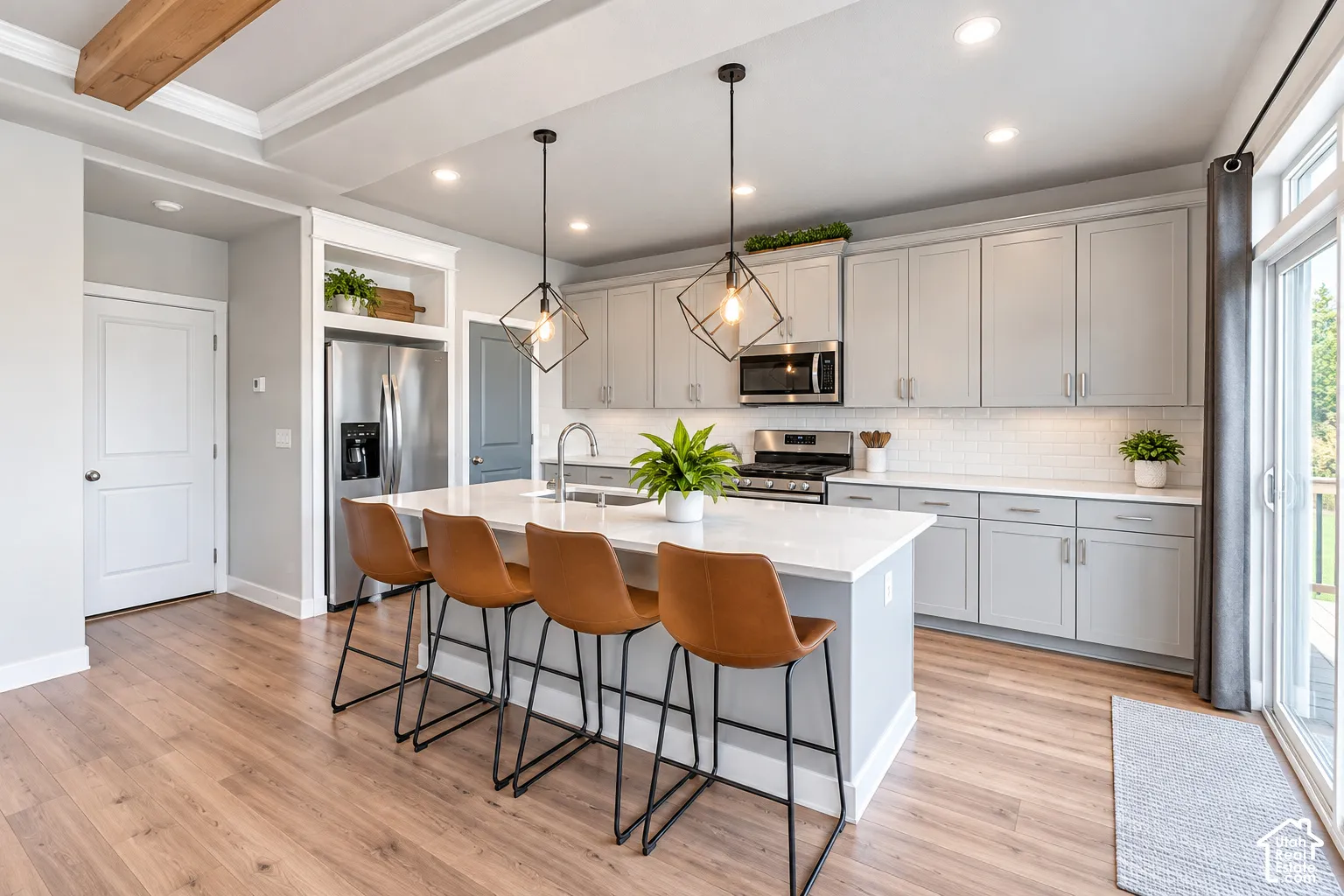 Kitchen featuring wood-finish flooring, an island with seating, stainless steel appliances, light gray cabinetry, and a sliding glass door