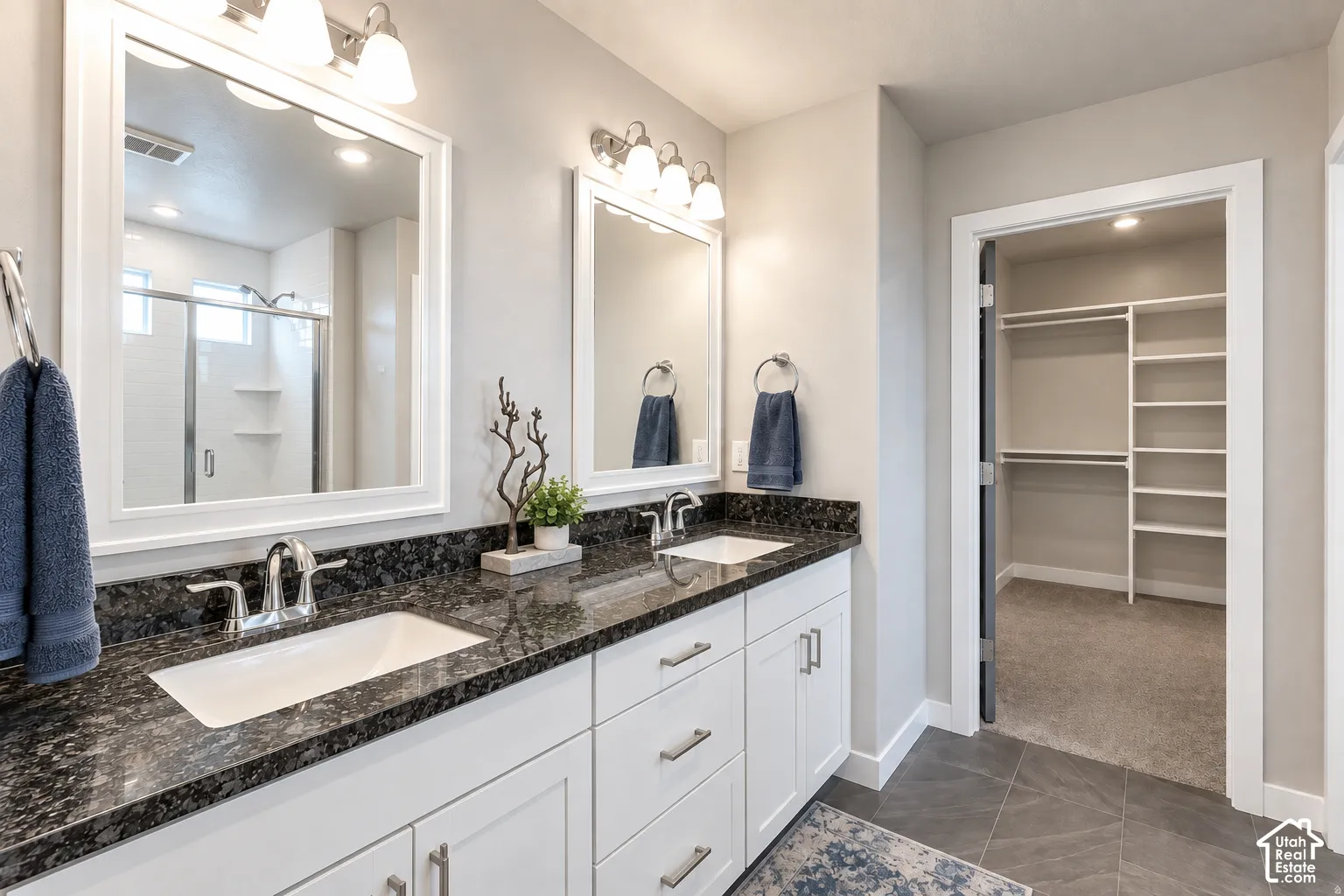 Primary Bathroom with double vanity with polished chrome fixtures and dark speckled countertops