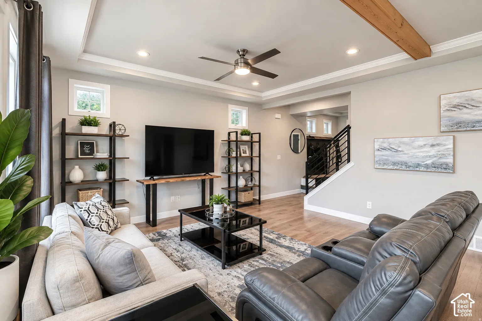 Tray ceiling with crown molding, recessed lighting, wood-finish flooring, exposed wood beam accent, and a modern ceiling fan