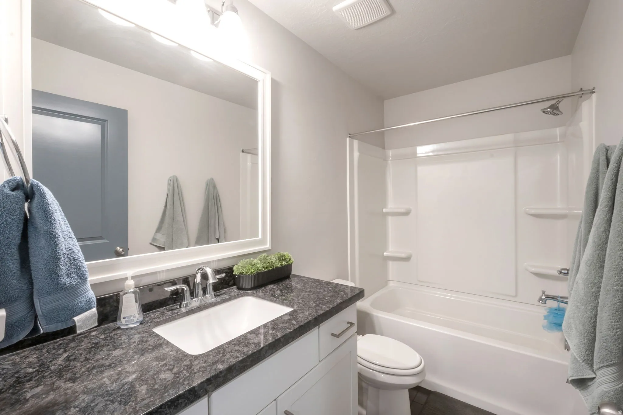 Full bathroom featuring a white vanity with dark countertop and integrated sink