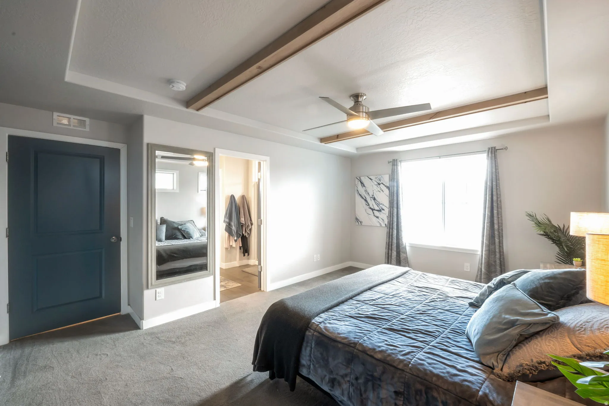 Spacious primary bedroom featuring neutral carpeting, a ceiling fan with integrated lighting, and large windows