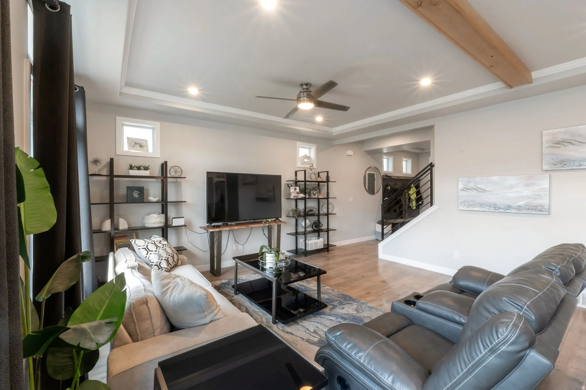 Spacious living area featuring laminate flooring, a tray ceiling with recessed lighting and a ceiling fan