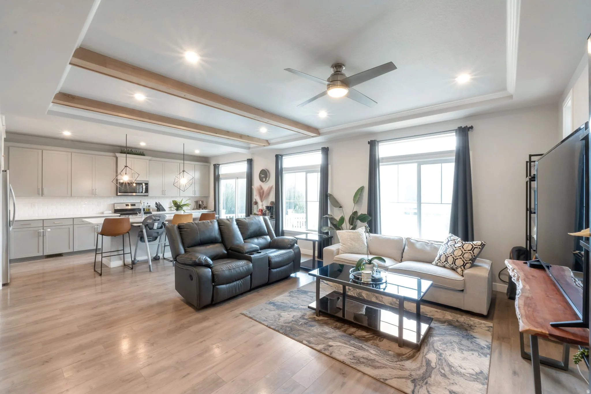 Open-concept living area featuring laminate flooring, a tray ceiling with recessed lighting