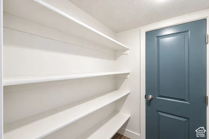 Built-in shelving with multiple levels, painted interior door, neutral wall color, and wood-finish flooring