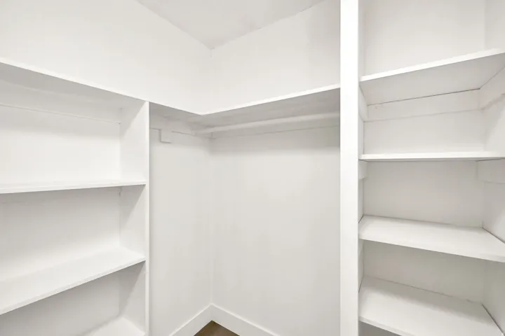 White built-in shelving, white walls, and a hanging rod