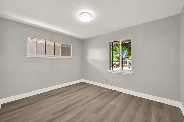Wood-finish flooring, light gray walls, white trim, and a flush-mount ceiling light