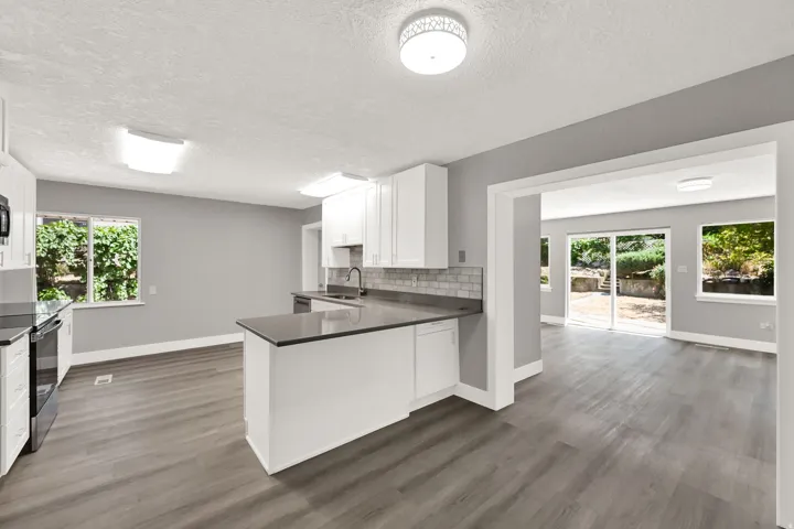 Kitchen featuring white cabinetry, dark countertops, a subway tile backsplash, and stainless steel appliances