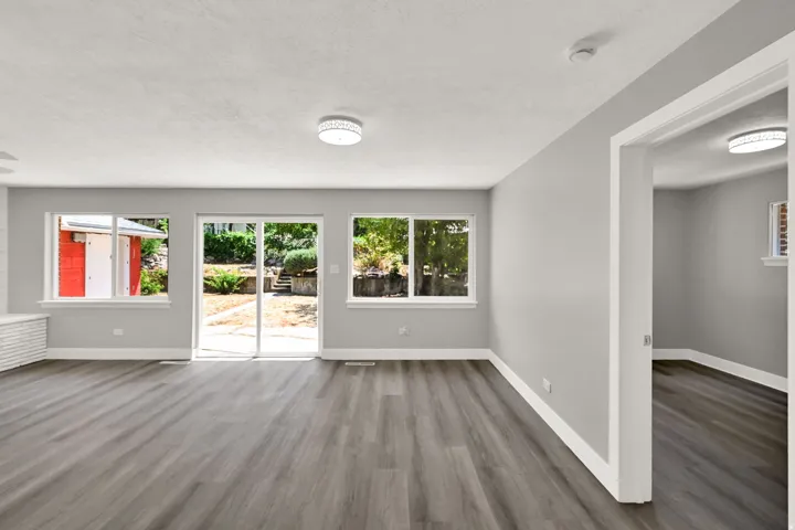 Wood-finish flooring, light gray wall paint, white trim, recessed lighting, and sliding glass door