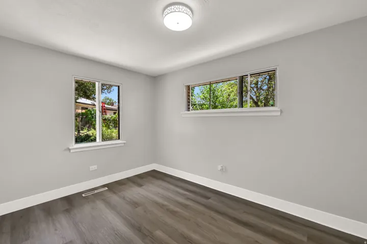 Light gray painted walls, wood-finish flooring, white trim, and a contemporary ceiling light fixture