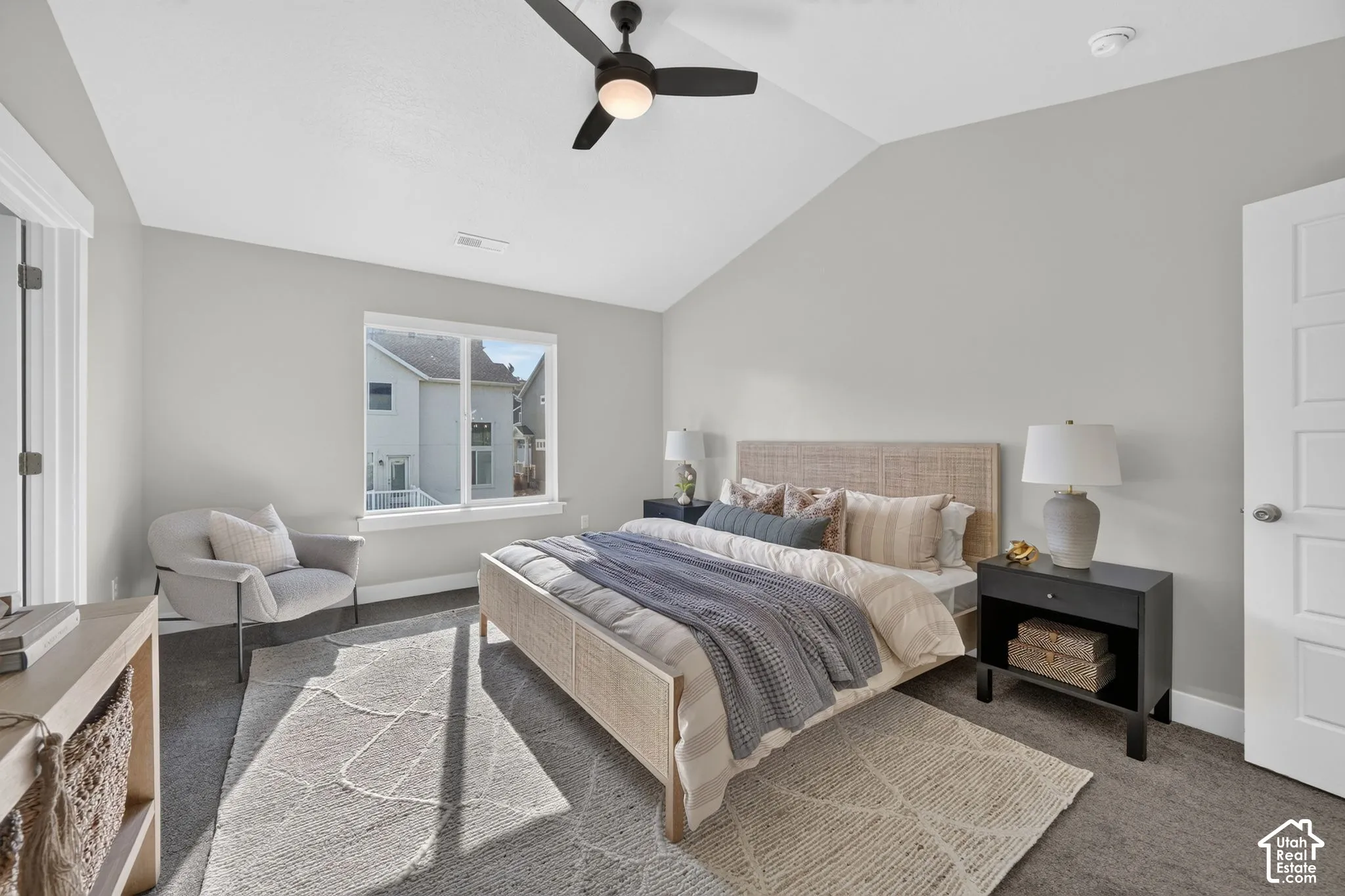 Spacious primary bedroom featuring vaulted ceilings, ceiling fan with integrated lighting, large bay window with natural light, wood-finish flooring, and neutral paint throughout