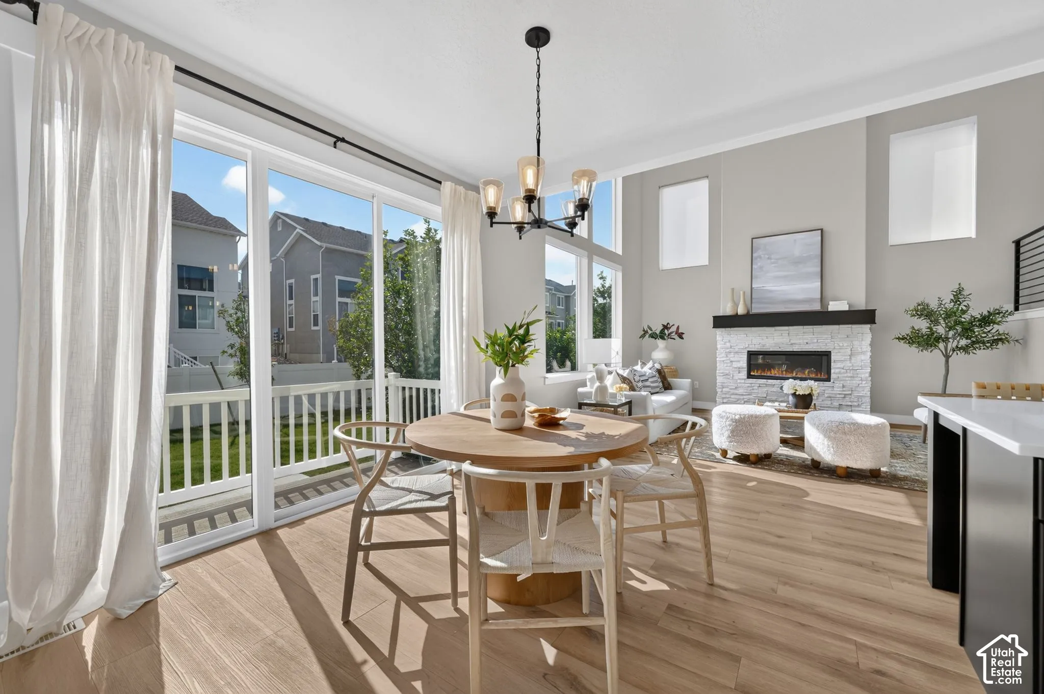 Spacious living area featuring high ceilings, wood-finish flooring, a contemporary fireplace with a stone surround, and an elegant chandelier