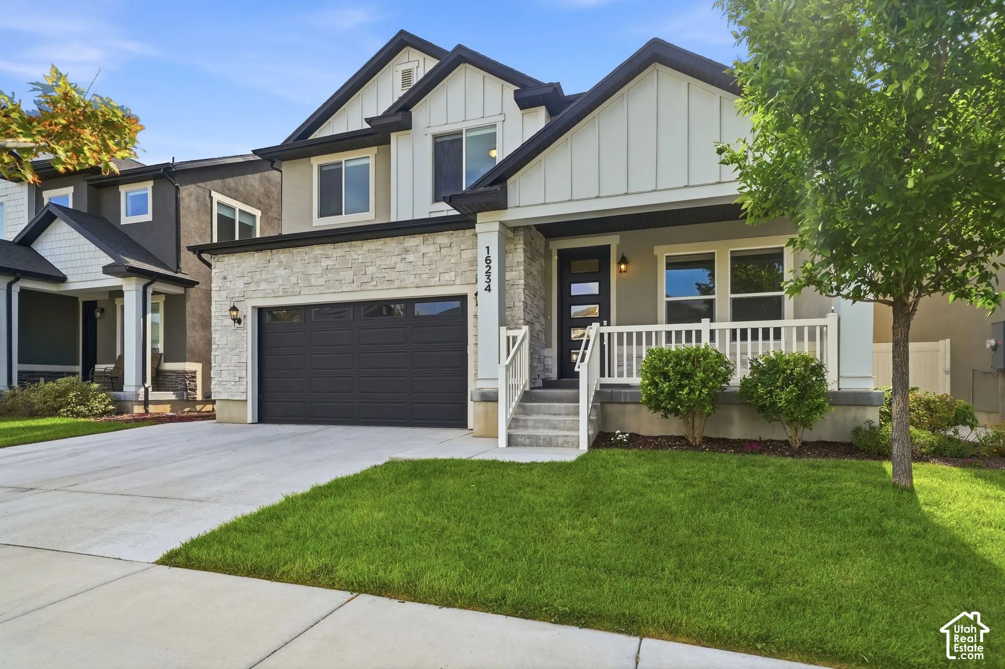 Contemporary exterior with stone facade accents, covered front porch, and a two-car garage