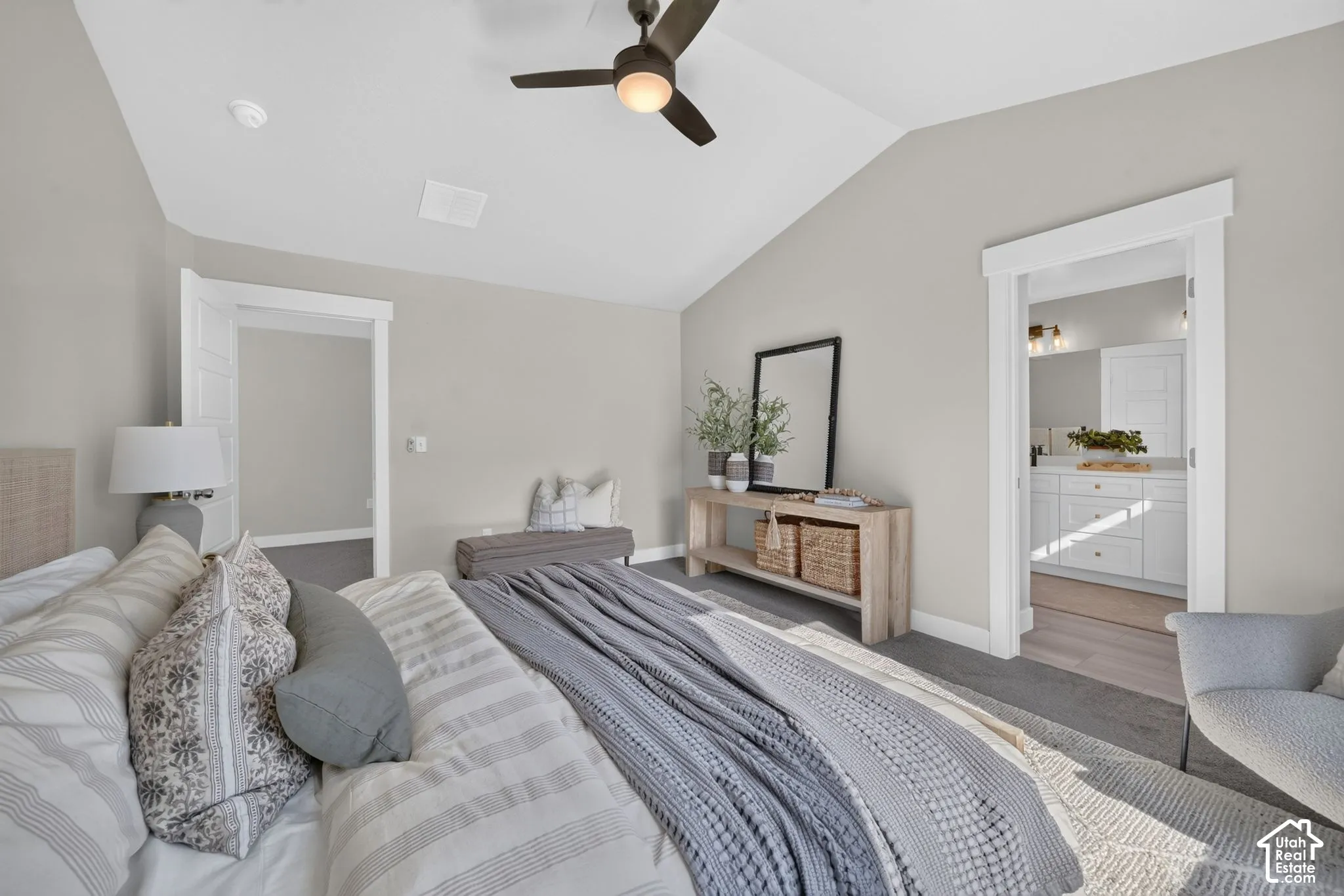 Vaulted ceiling with a ceiling fan, light gray wall paint, and gray carpeting