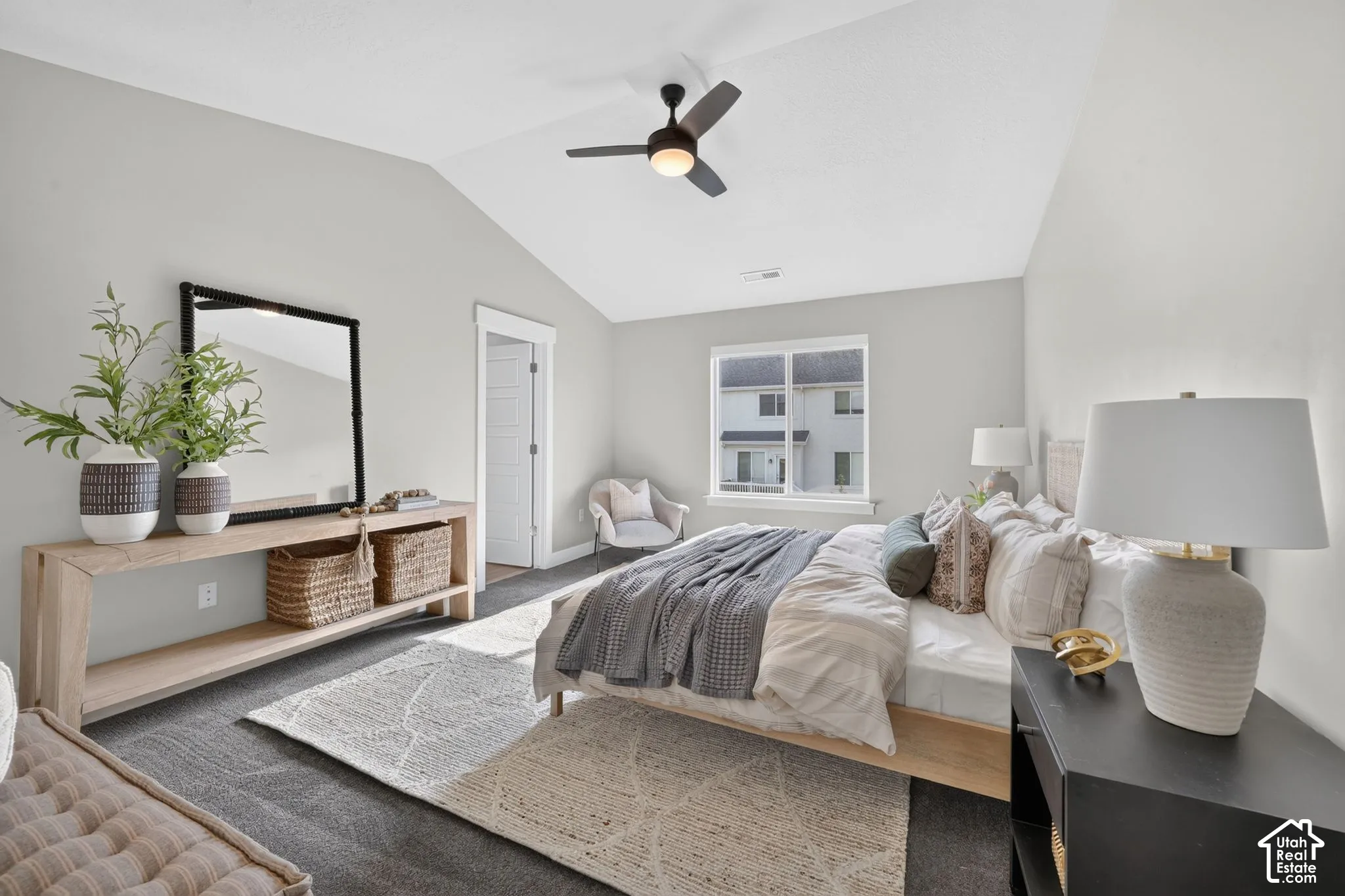 Vaulted ceiling with a ceiling fan, window with white trim, and light grey walls
