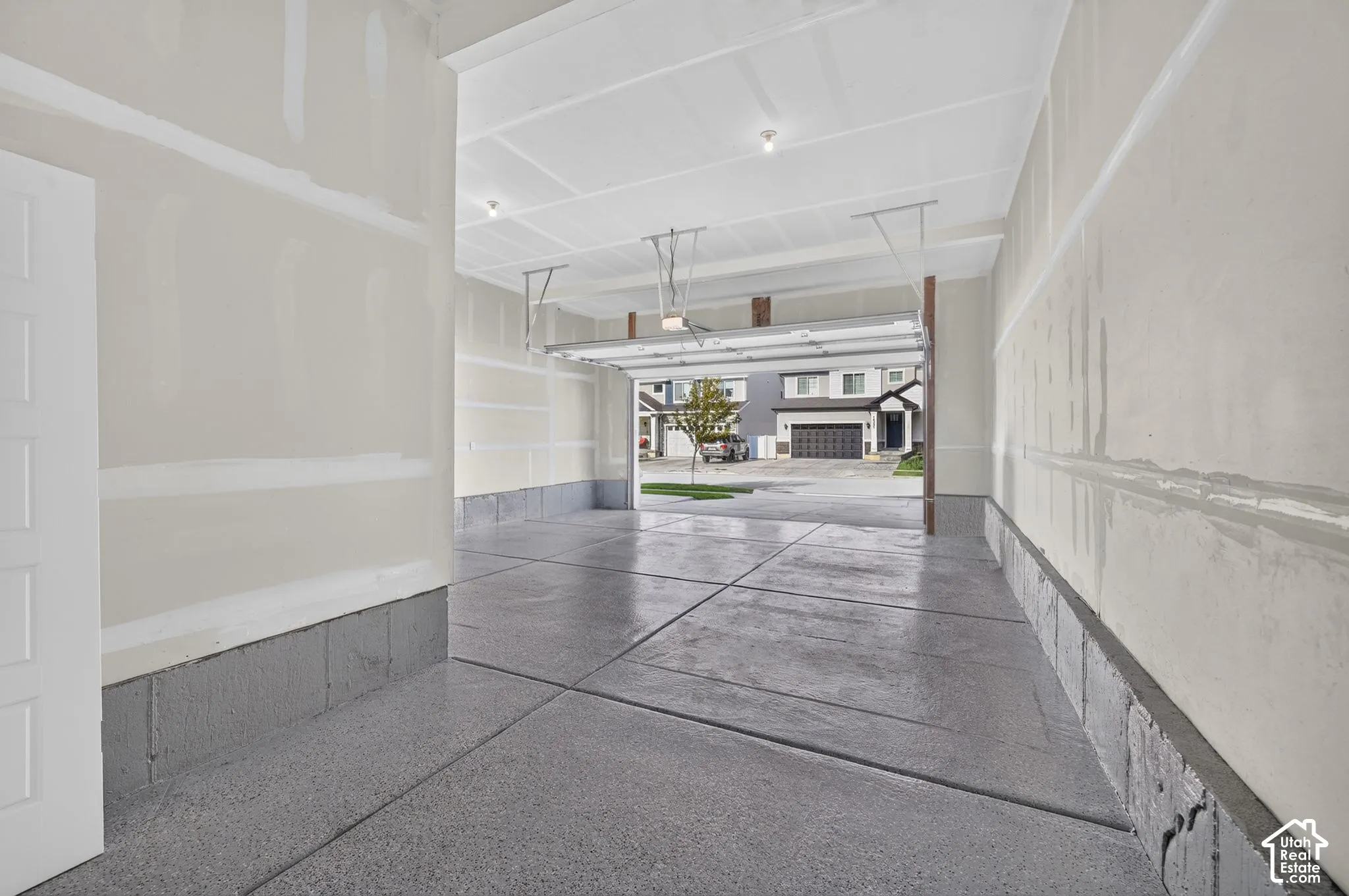Expansive garage space with a finished concrete floor, unfinished drywall, and exposed ceiling joists