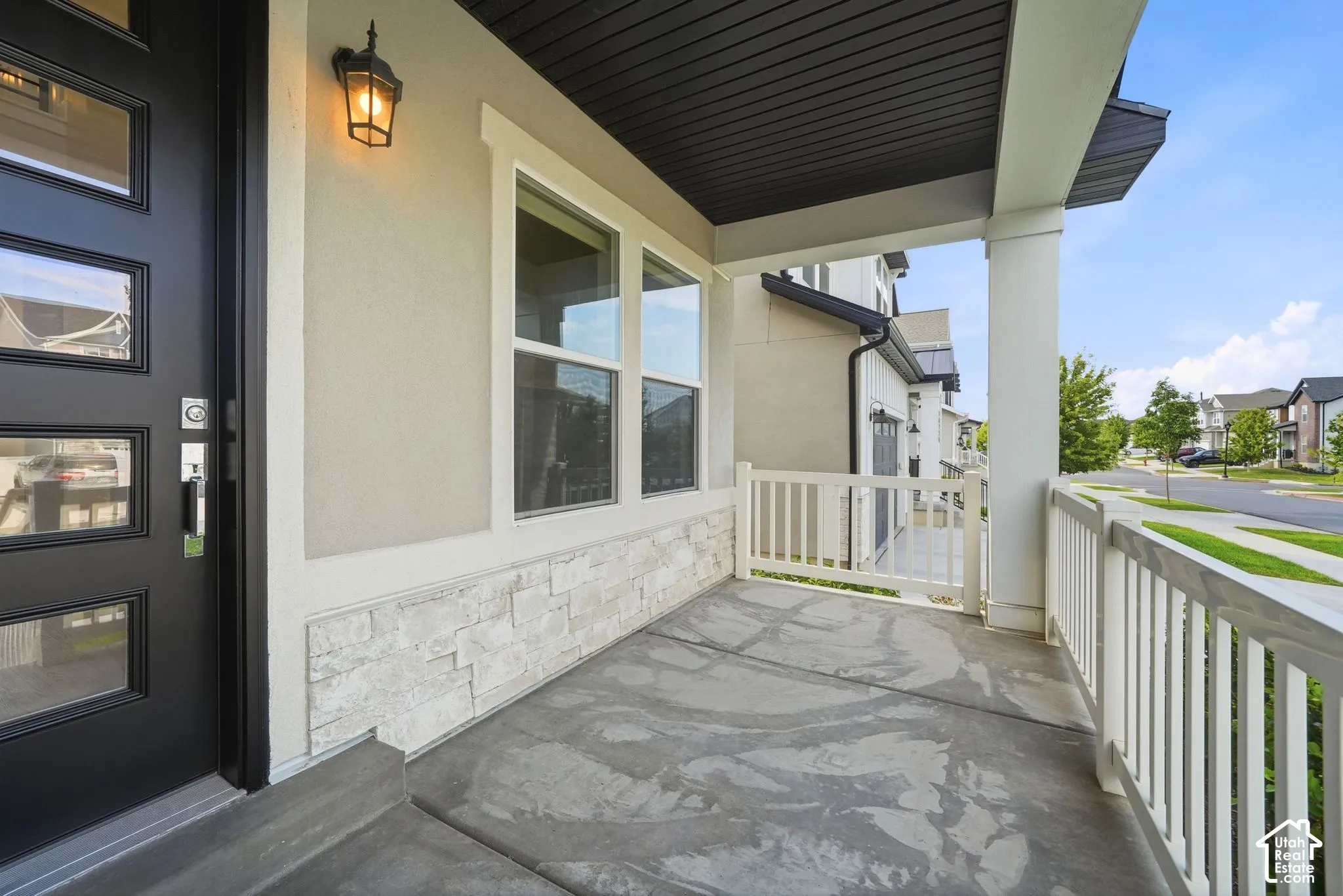 Covered front porch with concrete flooring and white railing