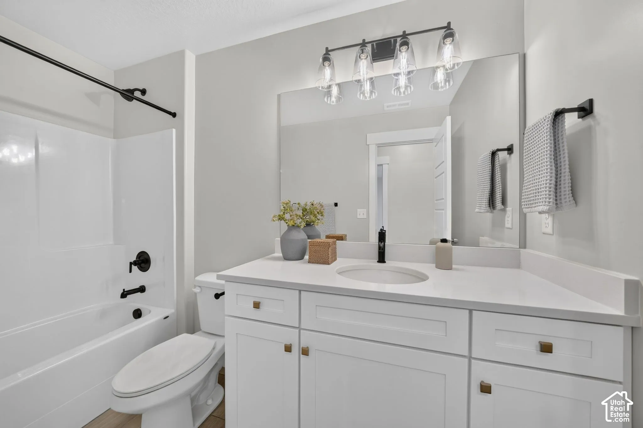 White vanity with a solid surface countertop, rectangular undermount sink, and matte black faucet
