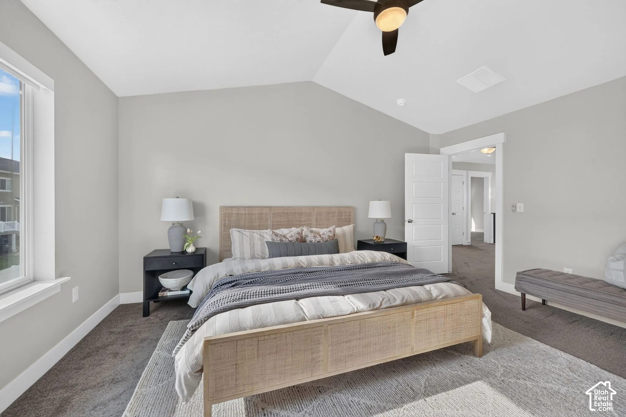 Vaulted ceiling with a ceiling fan, light gray wall paint, white trim throughout, and a window with natural light