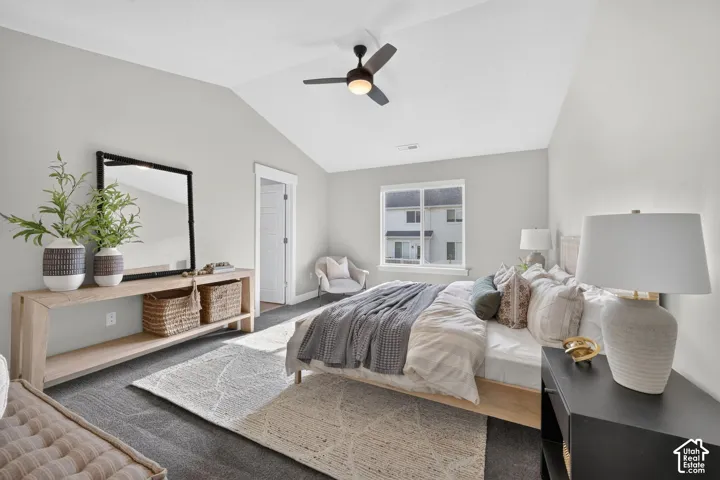 Vaulted ceiling with a ceiling fan, window with white trim, and light grey walls