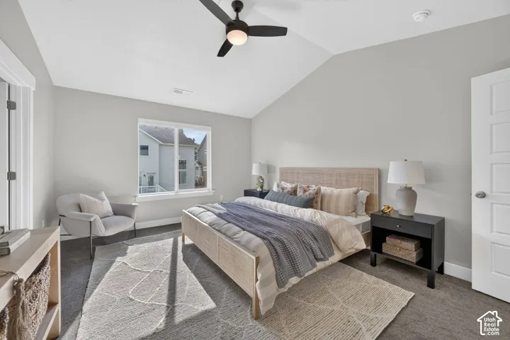 Spacious primary bedroom featuring vaulted ceilings, ceiling fan with integrated lighting, large bay window with natural light, wood-finish flooring, and neutral paint throughout