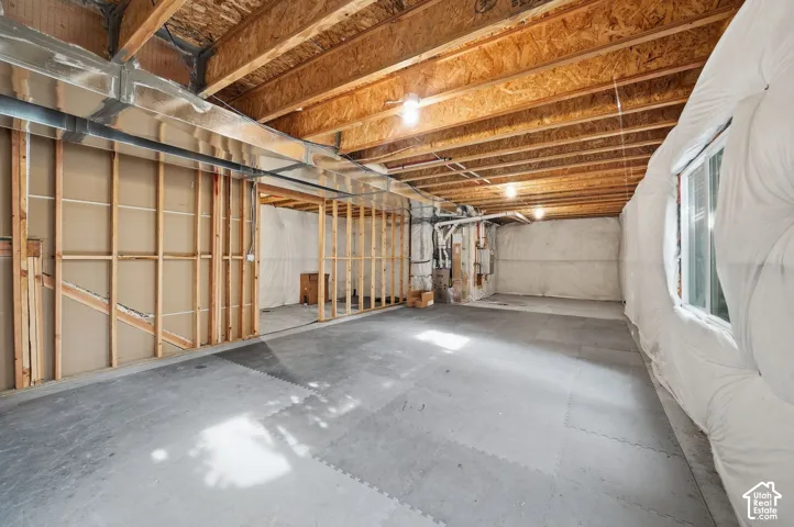 Unfinished lower level featuring exposed wood joist ceilings, partial wood stud framing, concrete flooring, and perimeter insulation wrap
