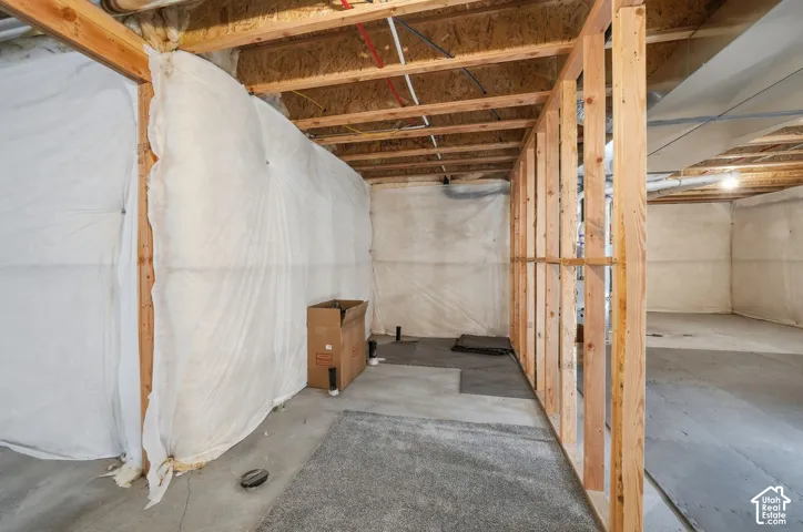Unfinished space featuring exposed timber framing, concrete flooring, and insulated foundation walls
