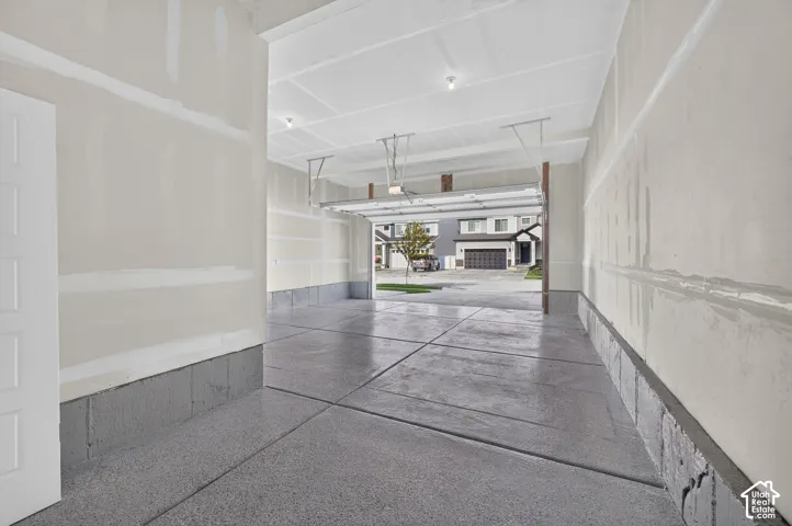 Expansive garage space with a finished concrete floor, unfinished drywall, and exposed ceiling joists