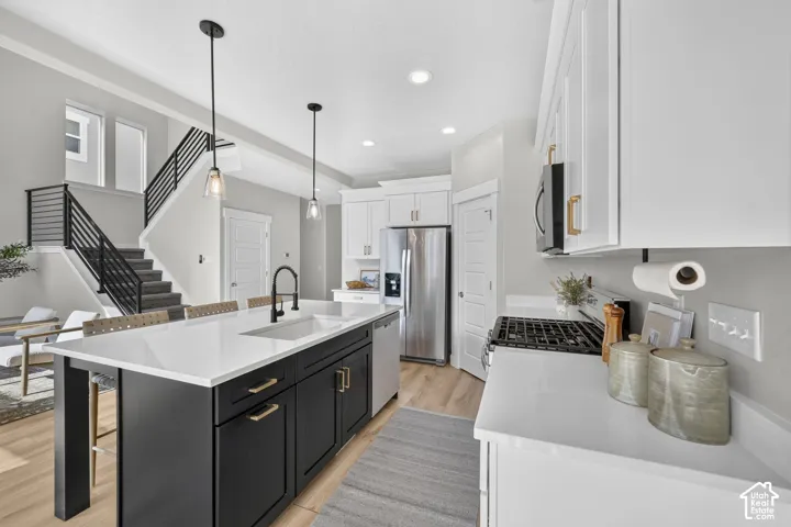 Contemporary kitchen featuring an expansive center island with seating, white countertops, built-in stainless steel appliances, and wood-finish flooring