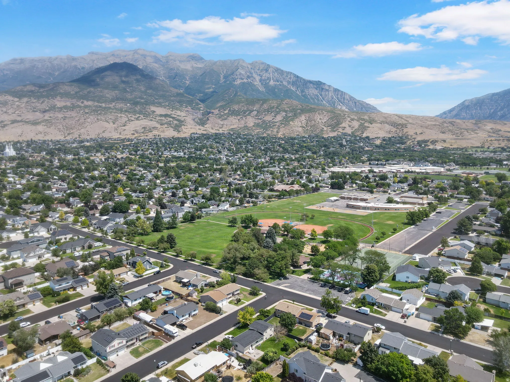 Expansive mountain backdrop with a residential community featuring established homes, green spaces, and community facilities