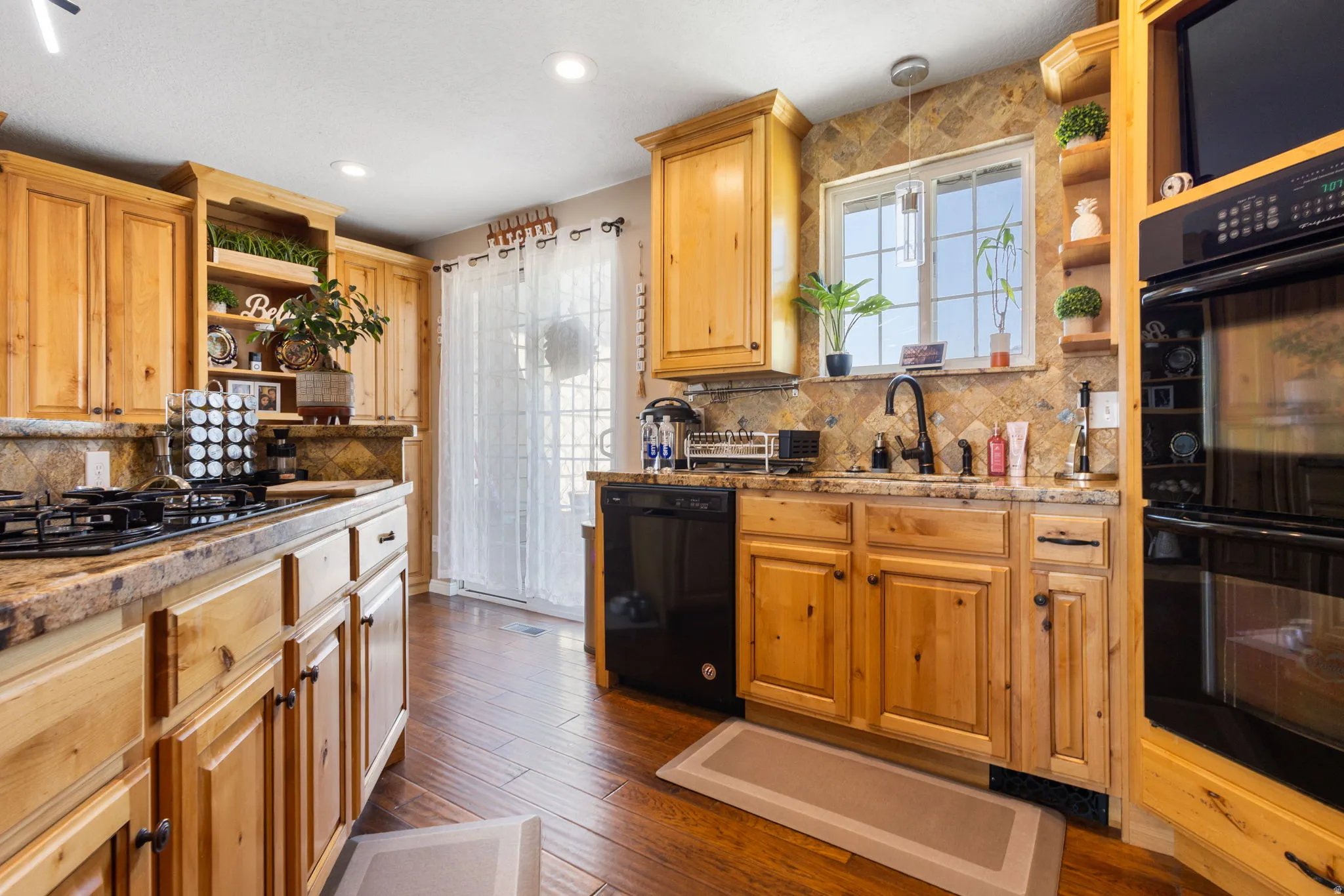 Wood-finish flooring, recessed lighting, wood cabinetry, built-in double ovens, and a built-in cooktop