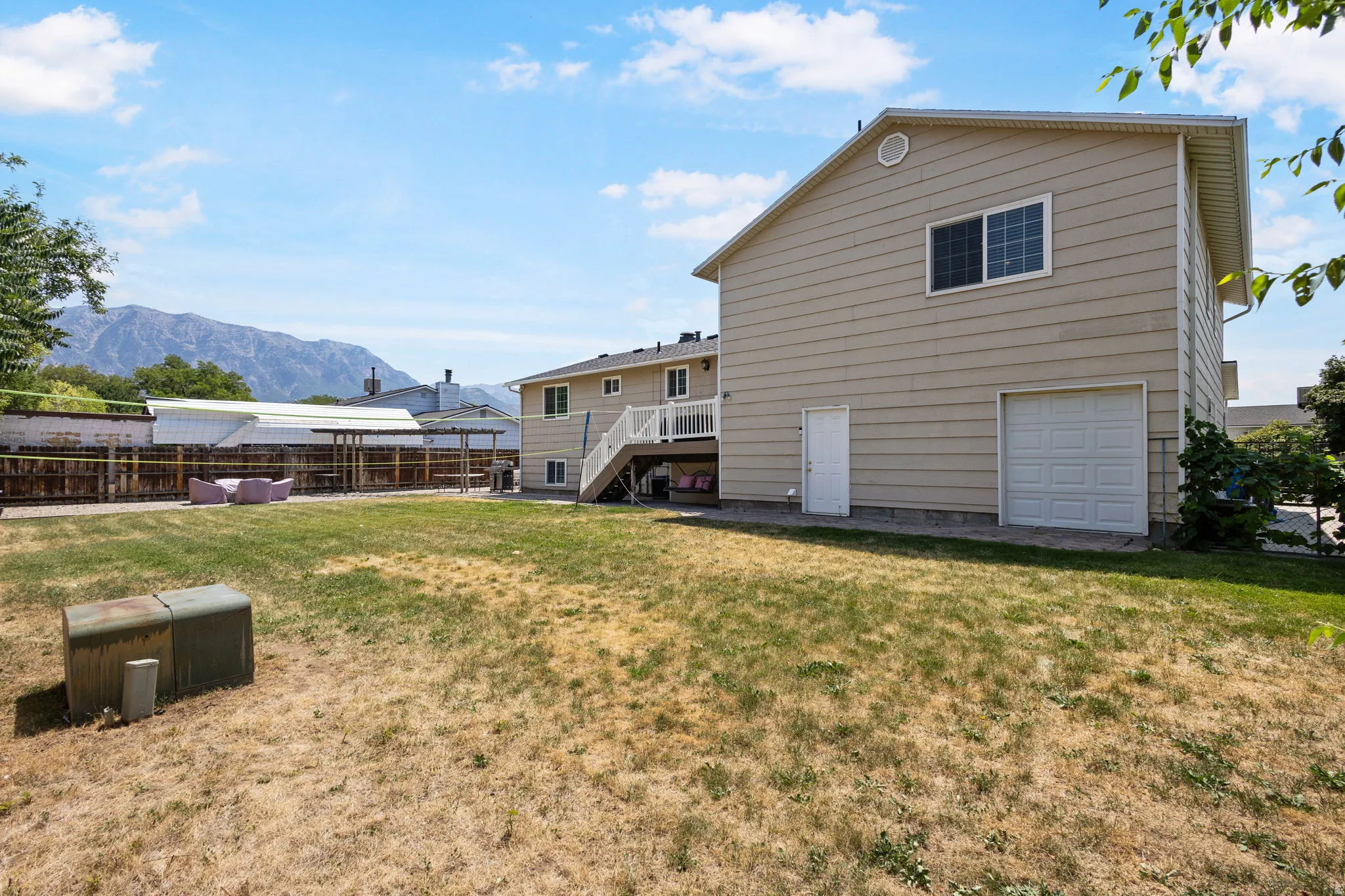 Expansive outdoor space with a mountain backdrop, featuring a multi-story exterior, white deck, and a garage door