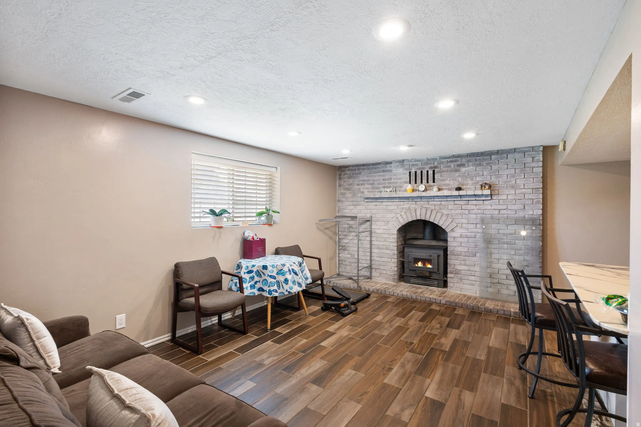Wood-finish flooring, recessed lighting, wood-burning stove with brick surround, built-in window, and a built-in counter